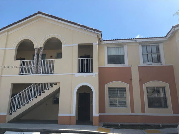 Front view of a two-story building with arched balconies and a staircase.