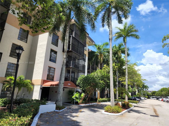 Front view of a multi-story residential building with balconies and palm trees.
