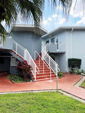 Front view of a two-story residential building with exterior stairs leading to the upper level.