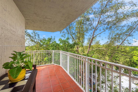 Balcony view with railing overlooking greenery and sky.