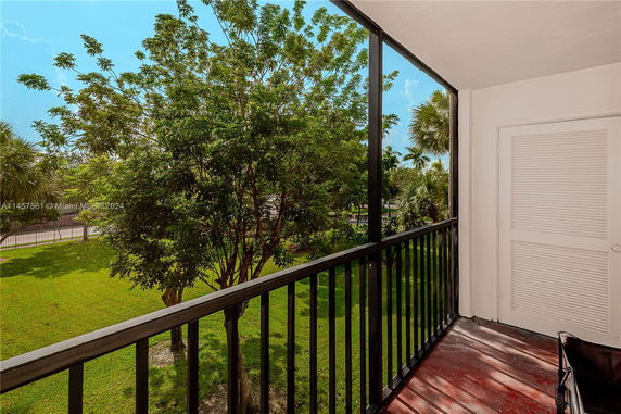 View of trees and green landscape from a balcony area.