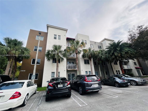 Front view of a multi-story residential building with balconies and parking area.