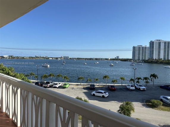 View from balcony showing a water body with boats and distant high-rise buildings.