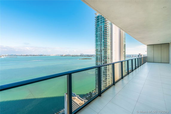 Wide-angle view of a balcony overlooking a body of water with high-rise buildings visible in the distance.