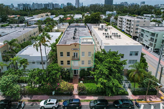 Aerial view of a multi-story building with adjacent structures and greenery.