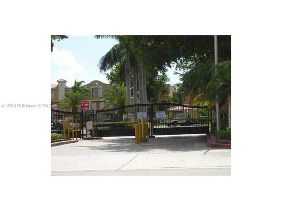 Front view of a gated entrance to a residential complex with trees and buildings in the background.