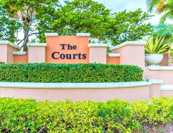 Sign with 'The Courts' surrounded by greenery and decorative planters.