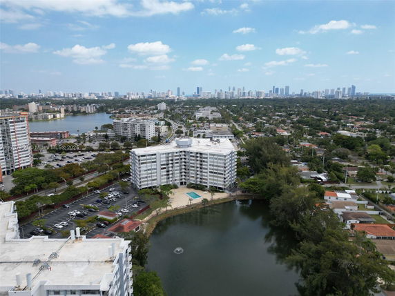 Elevated panoramic view of a cityscape with high-rise buildings and a lake in the foreground.