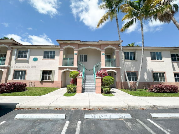 Front view of a two-story building with a central staircase and reserved parking spaces.