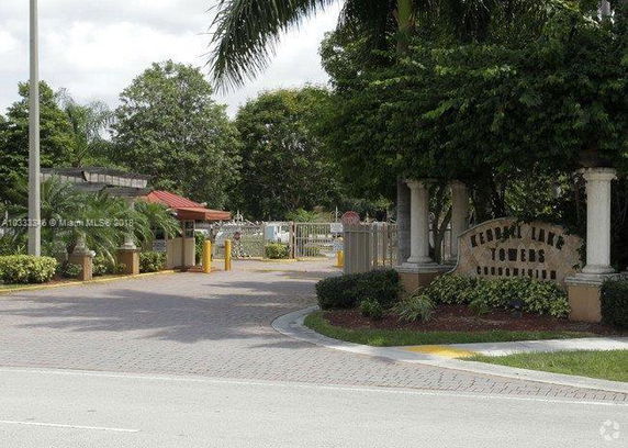 Entrance view of a gated condominium community with surrounding greenery and signage.