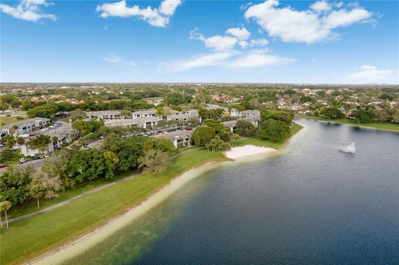 Aerial view of a complex of buildings near a large body of water with surrounding greenery.