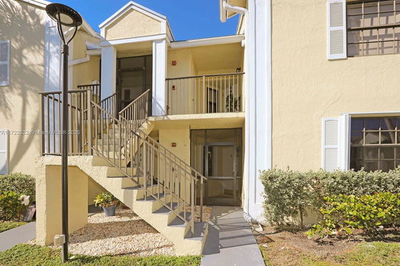 Front view of a two-story beige building with an external staircase.