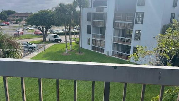 View from a balcony overlooking a grassy area and a multi-story residential building.