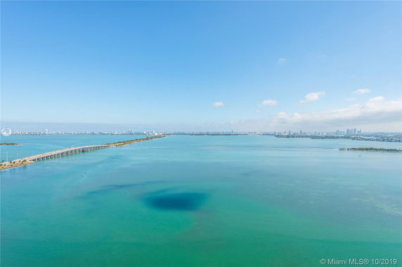 Panoramic view of a bay with a bridge and distant city skyline.