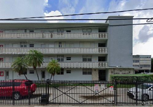 Front view of a multi-story apartment building with balconies and a gated entrance.