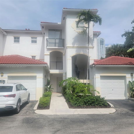 Front view of a multi-story house with a red tiled roof and two garages.
