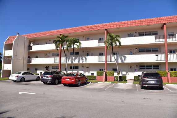 Front view of a three-story residential building with parking area in front.