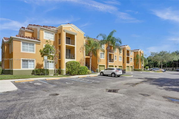 Front view of a multi-story apartment building with balconies and parking area.