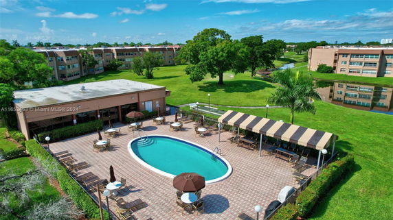 Outdoor swimming pool area with surrounding patio and buildings in the background.