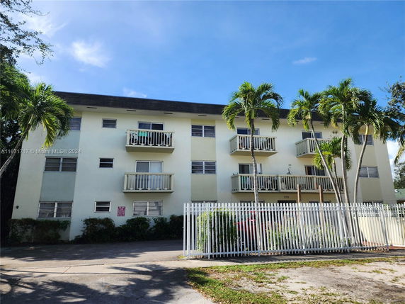 Front view of a three-story residential building with balconies and a gated entrance.