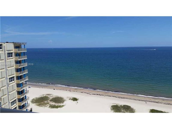 Panoramic view of a beach and ocean with a building on the left.
