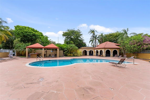 View of an outdoor swimming pool area with a surrounding patio and lounge chairs.