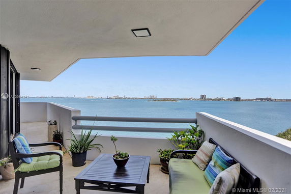Balcony view overlooking a large body of water with distant city skyline.