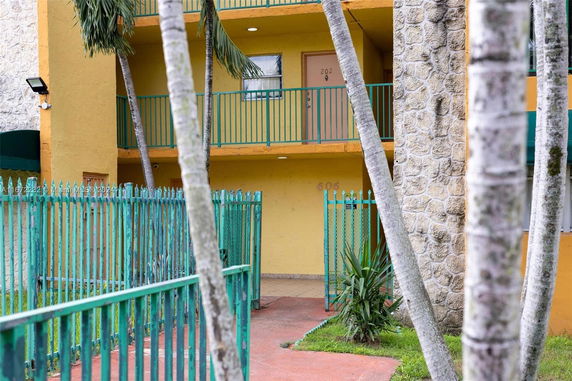 Front view of a multi-story building with balconies and a gated entrance.