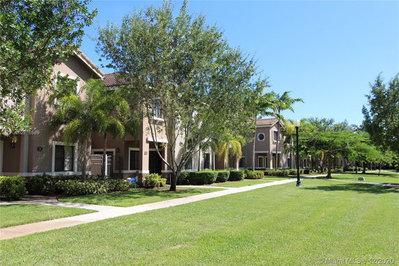 Front view of a row of multi-story residential houses with tan exteriors and brown roofs.