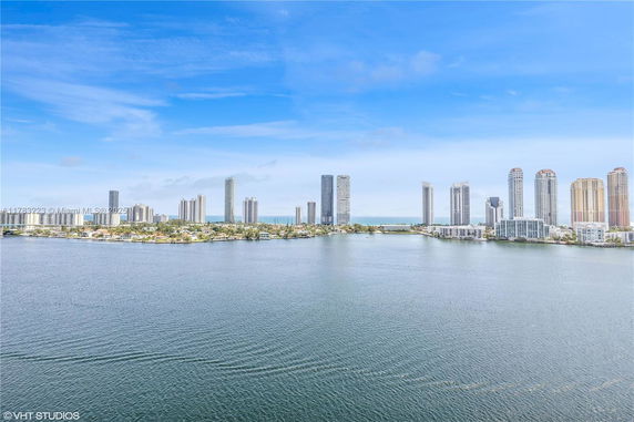 Panoramic view of a city skyline with tall buildings and water in the foreground.