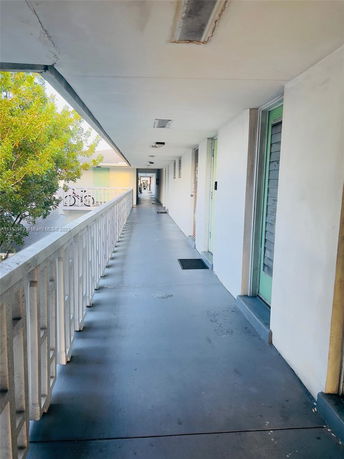 Outdoor hallway view with railing and doors.