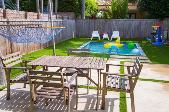 Backyard with a small swimming pool, hammock, and outdoor seating area.
