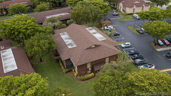Aerial view of a neighborhood with buildings, trees, and parking areas.
