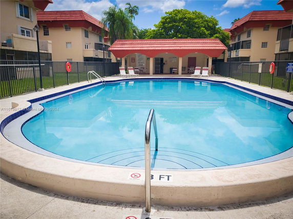 Outdoor swimming pool area with surrounding buildings.