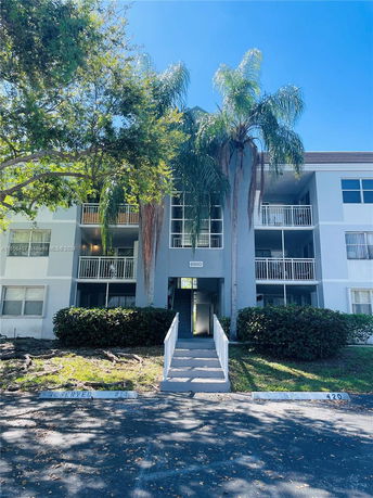 Front view of a multi-story building with balconies and a central walkway entrance.