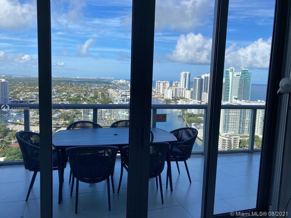 View from a high-rise balcony overlooking a cityscape and ocean.