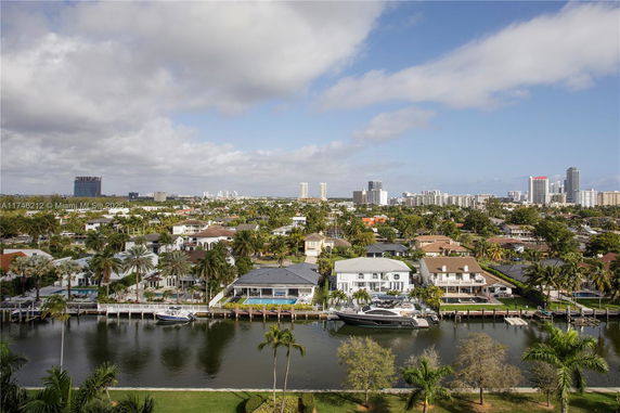 Panoramic view of residential area with waterway, boats, and tall buildings in the background.
