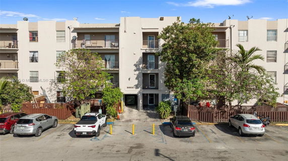 Front view of a multi-story residential building with balconies and parking area.