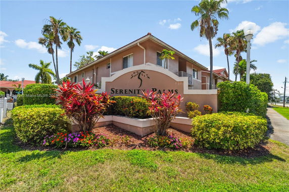 Front view of a multi-story residential building with a sign reading 'Serenity Palms'.