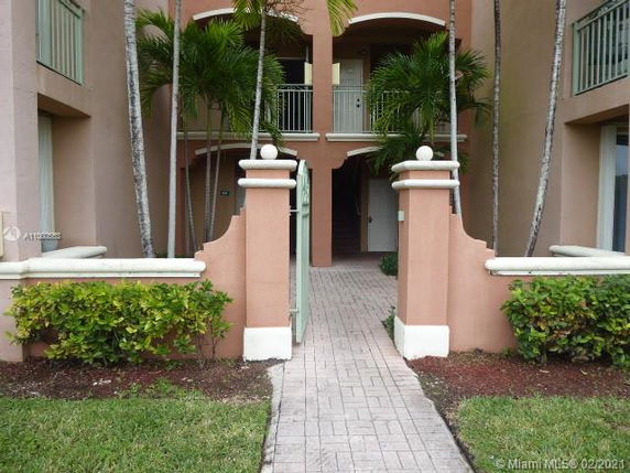 Front view of a multi-story residential building with balconies and a gated entrance.