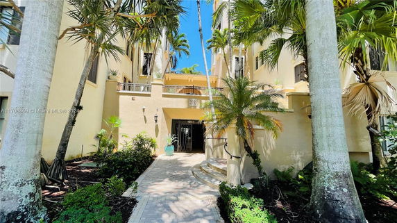 Front view of a multi-story building with entrance and surrounding palm trees.
