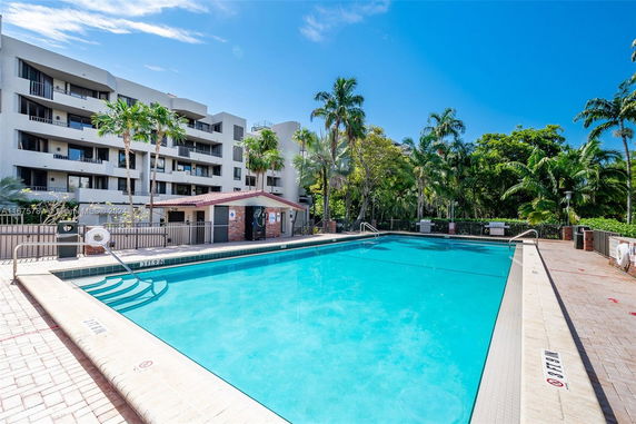 Outdoor swimming pool in front of a multi-story building with balconies.