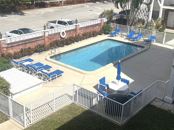 Outdoor swimming pool area with surrounding lounge chairs and a small table with chairs.