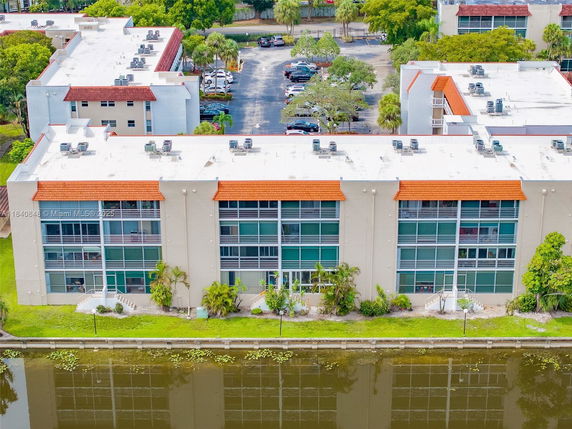 Front view of a multi-story residential building with large windows and a canal in the foreground.