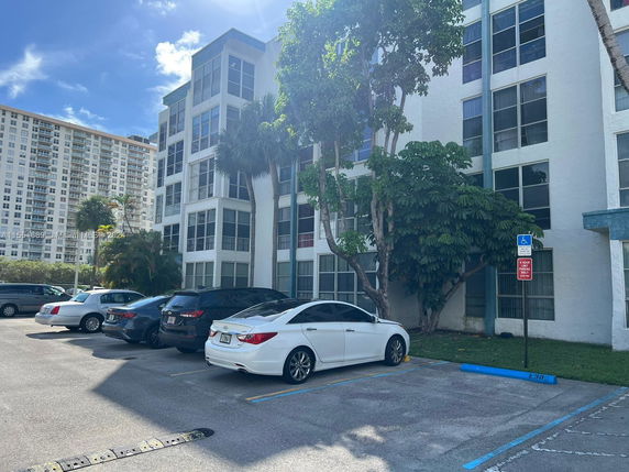Outdoor parking area in front of a multi-story residential building.