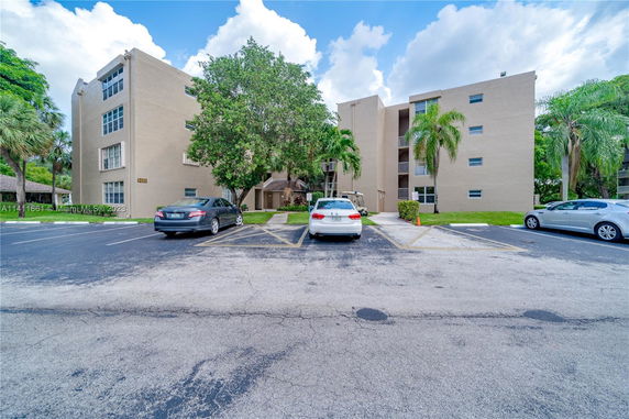 Front view of a three-story apartment building with parking area.