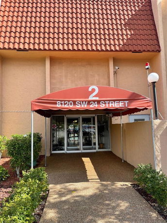 Front view of a building entrance with a red canopy and address 8120 SW 24 Street.