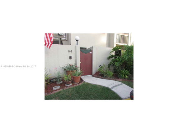 Front view of a building entrance with potted plants and an American flag.