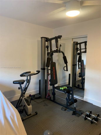 Room with exercise equipment including a home gym and stationary bike.