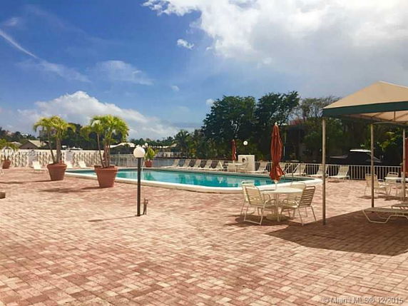 Outdoor pool area with lounge chairs and umbrellas.
